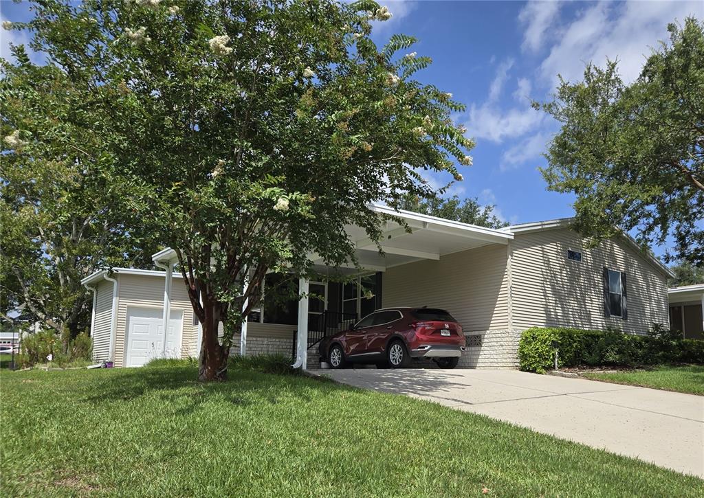 A single-story house with light siding, a carport, and a red car in the driveway — 2723 LAKE GRASSMERE CIRCLE UNIT 910, ZELLWOOD, FL