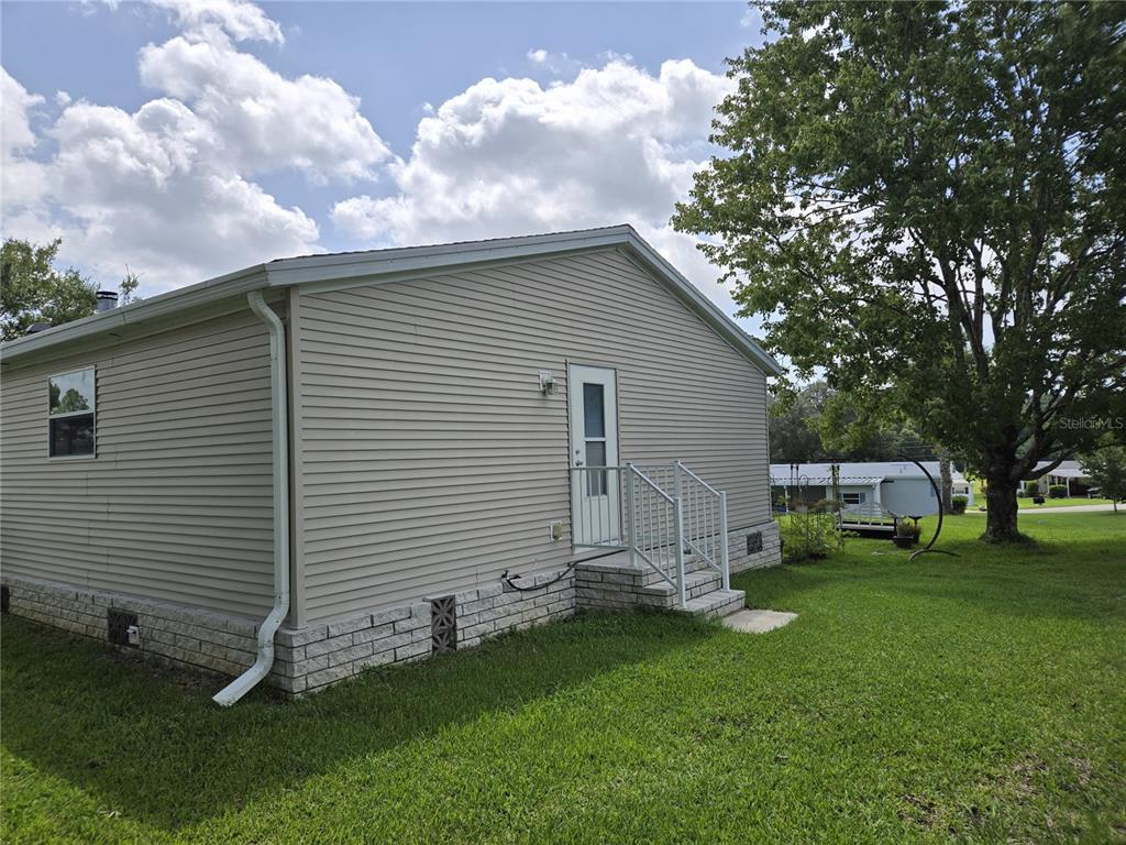 The exterior of a tan vinyl-sided house features a white door with metal stairs — 2723 LAKE GRASSMERE CIRCLE UNIT 910, ZELLWOOD, FL