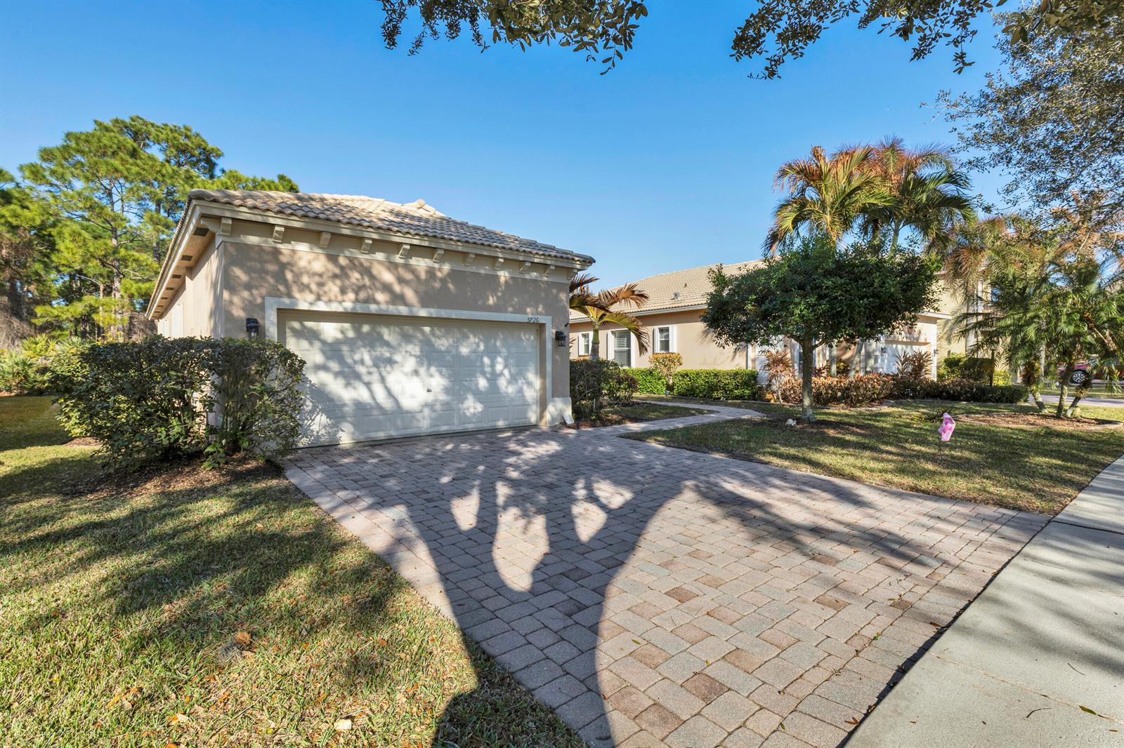 A paved driveway leads to a one-story house with a two-car garage and palm trees — 5726 Sterling Lake Drive, Fort Pierce FL 34951, FORT PIERCE, FL