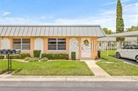 The exterior of a peach-colored building features a white door with a sunflower wreath — 11923 BOYNTON LANE UNIT B, NEW PORT RICHEY, FL