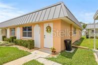 A living room and dining area with tile floors, a ceiling fan, and kitchen pass-through — 11923 BOYNTON LANE UNIT B, NEW PORT RICHEY, FL