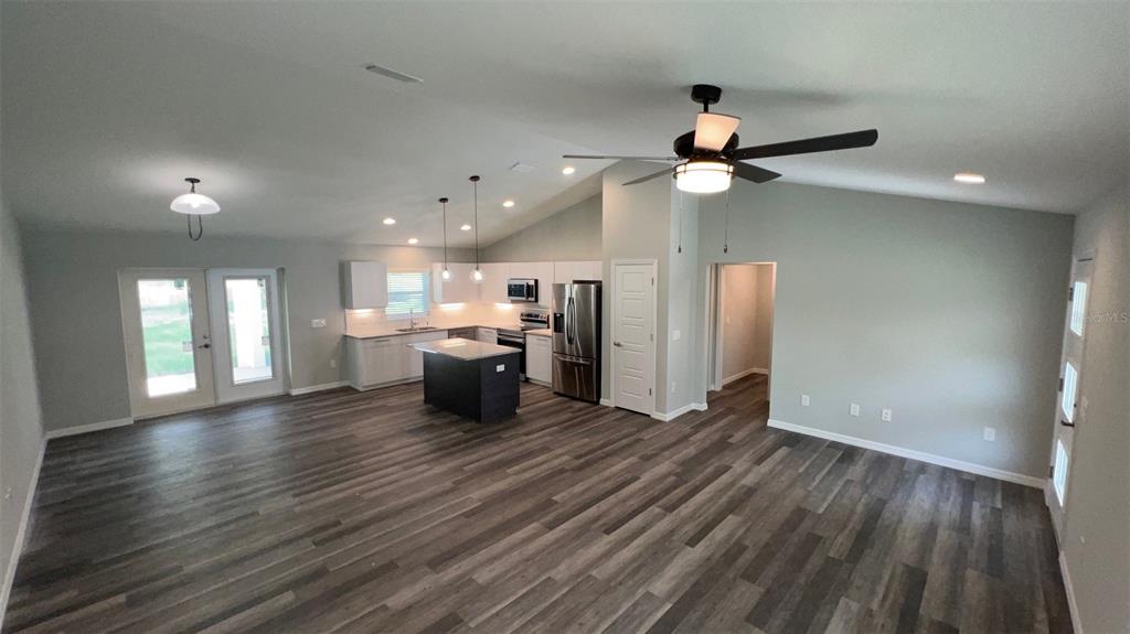 An open-concept kitchen and living area features wood-look flooring, white cabinetry, and a dark island — TBD FISHER LANE TRACK, OCKLAWAHA, FL