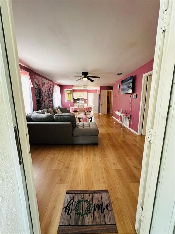A living room with wood flooring, a grey sectional sofa, and pink walls — 224 MONTEGO DRIVE, SEBRING, FL
