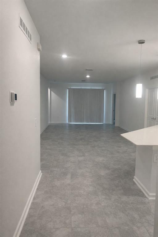 An open-concept living area features gray tile flooring, white walls, and a sliding glass door — 4086 GOOSEBERRY TRAIL, KISSIMMEE, FL