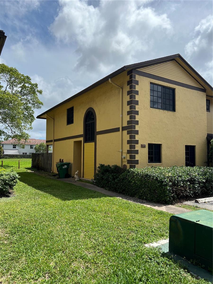 A two-story yellow stucco building features brown trim, a decorative corner column, and dark windows — 1126 NE 209th Ter, Miami FL 33179, MIAMI, FL