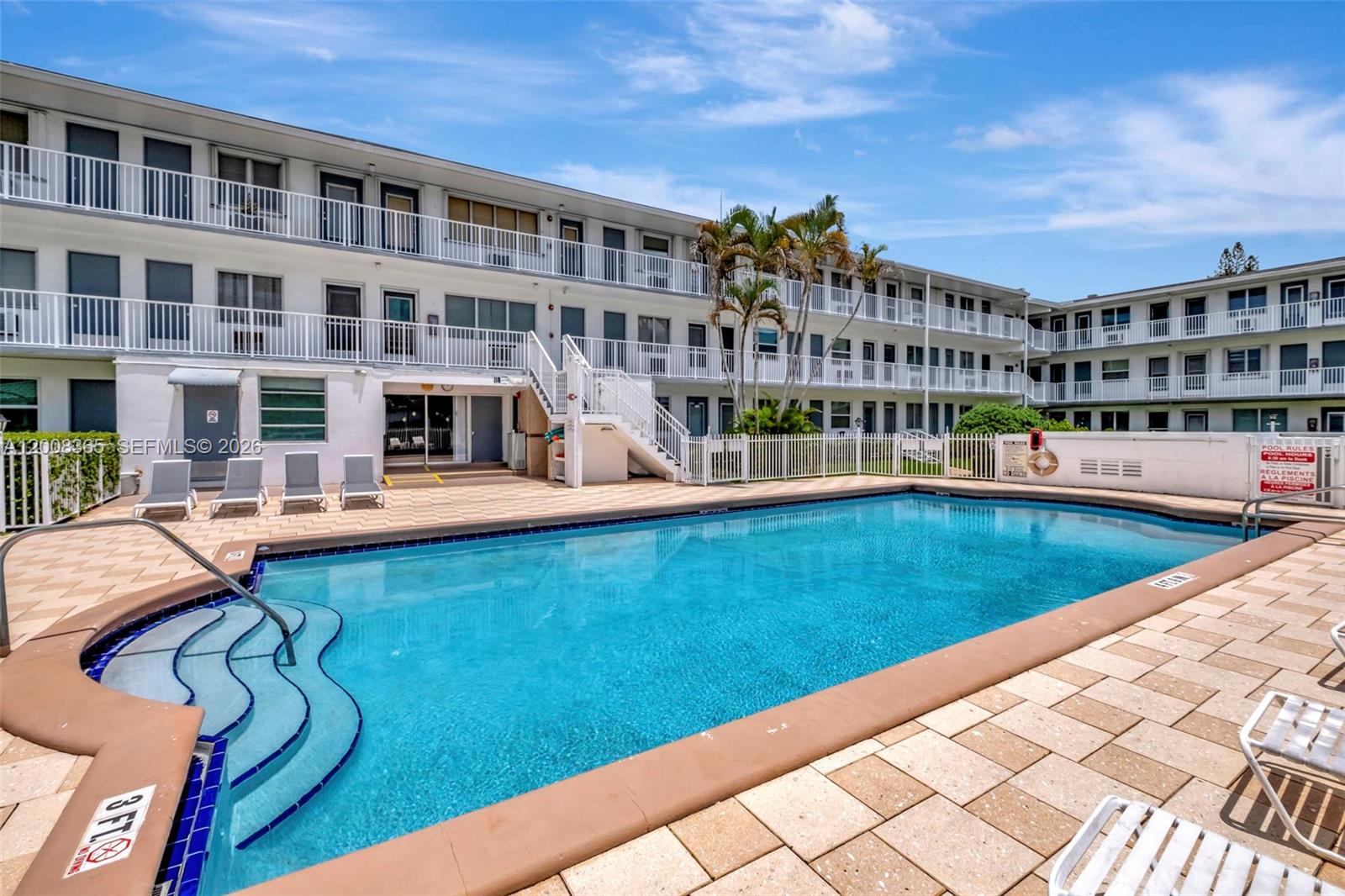 A swimming pool with a shallow entry area sits in front of a multi-story apartment building — 15610 NE 6th Ave # 23C, Miami FL 33162, MIAMI, FL