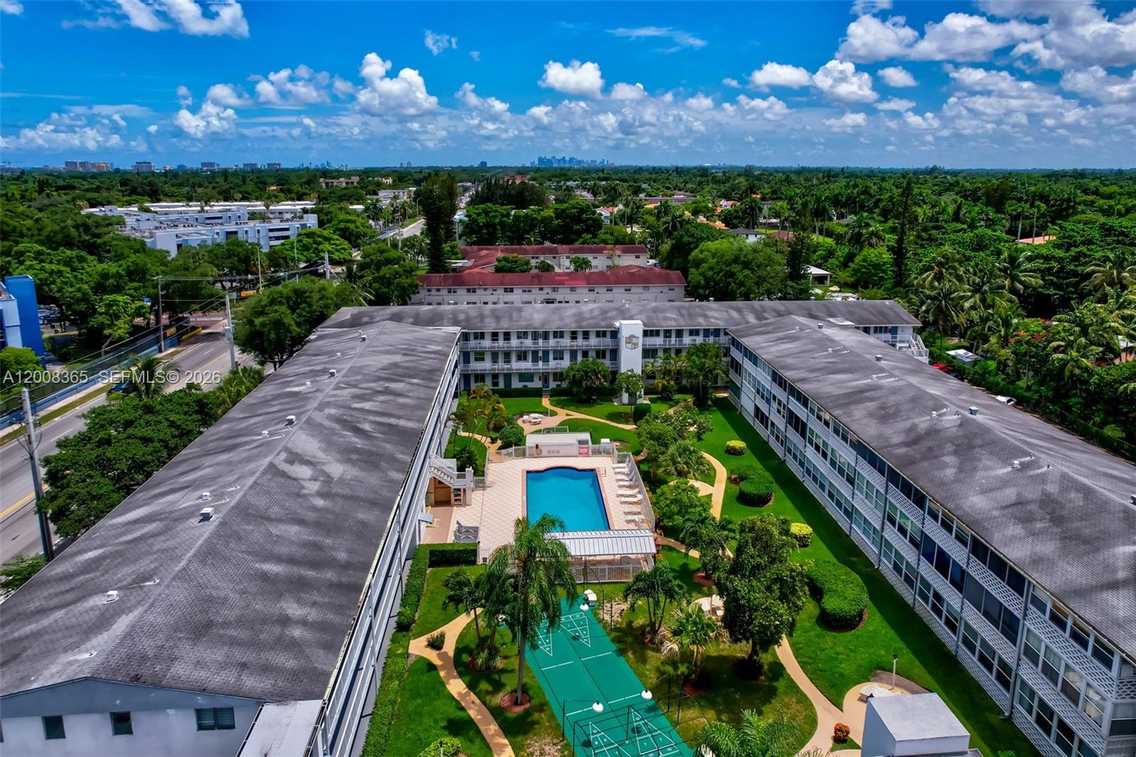 An aerial view shows a multi-story apartment complex with a central courtyard, pool, and court — 15610 NE 6th Ave # 23C, Miami FL 33162, MIAMI, FL