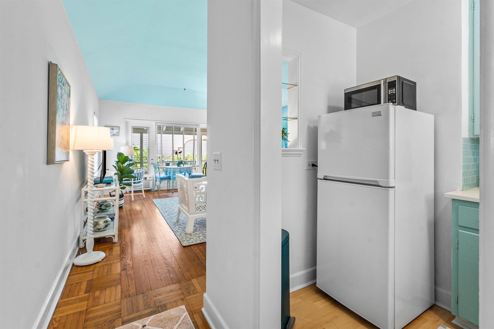 A white refrigerator sits in a kitchen area next to a bright, open living room — 424 Chilean Avenue # 4, Palm Beach FL 33480, PALM BEACH, FL