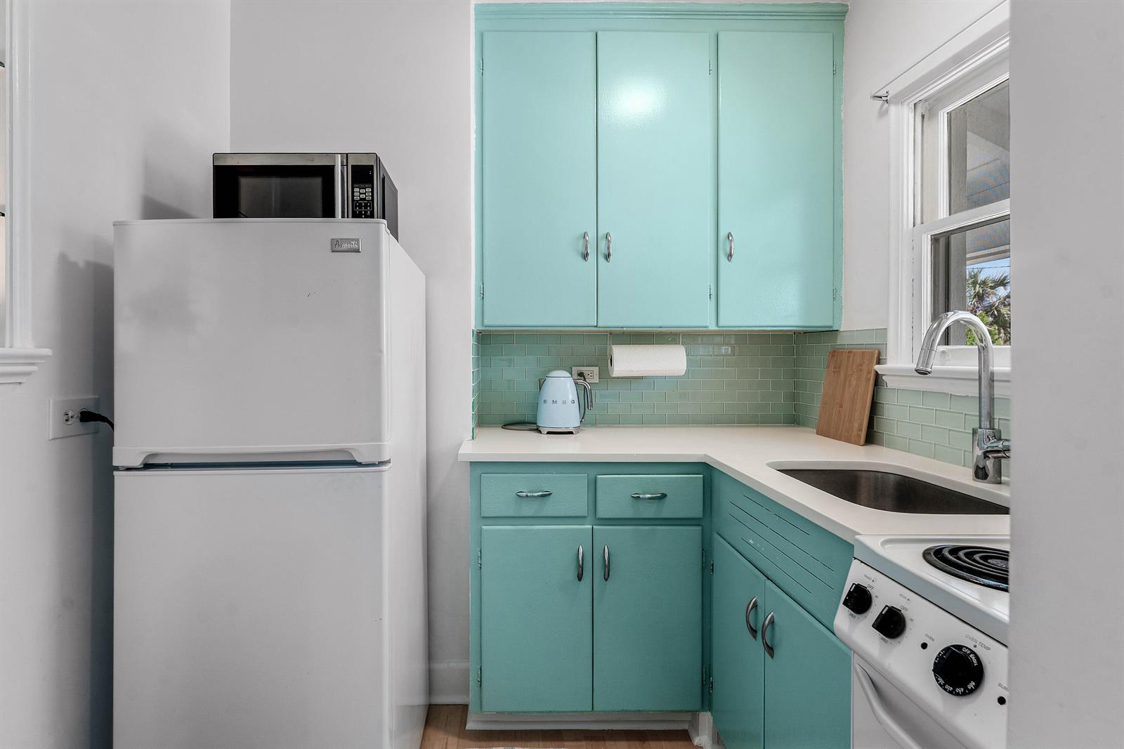 A small kitchen features turquoise cabinets, white appliances, and a light green subway tile backsplash — 424 Chilean Avenue # 4, Palm Beach FL 33480, PALM BEACH, FL