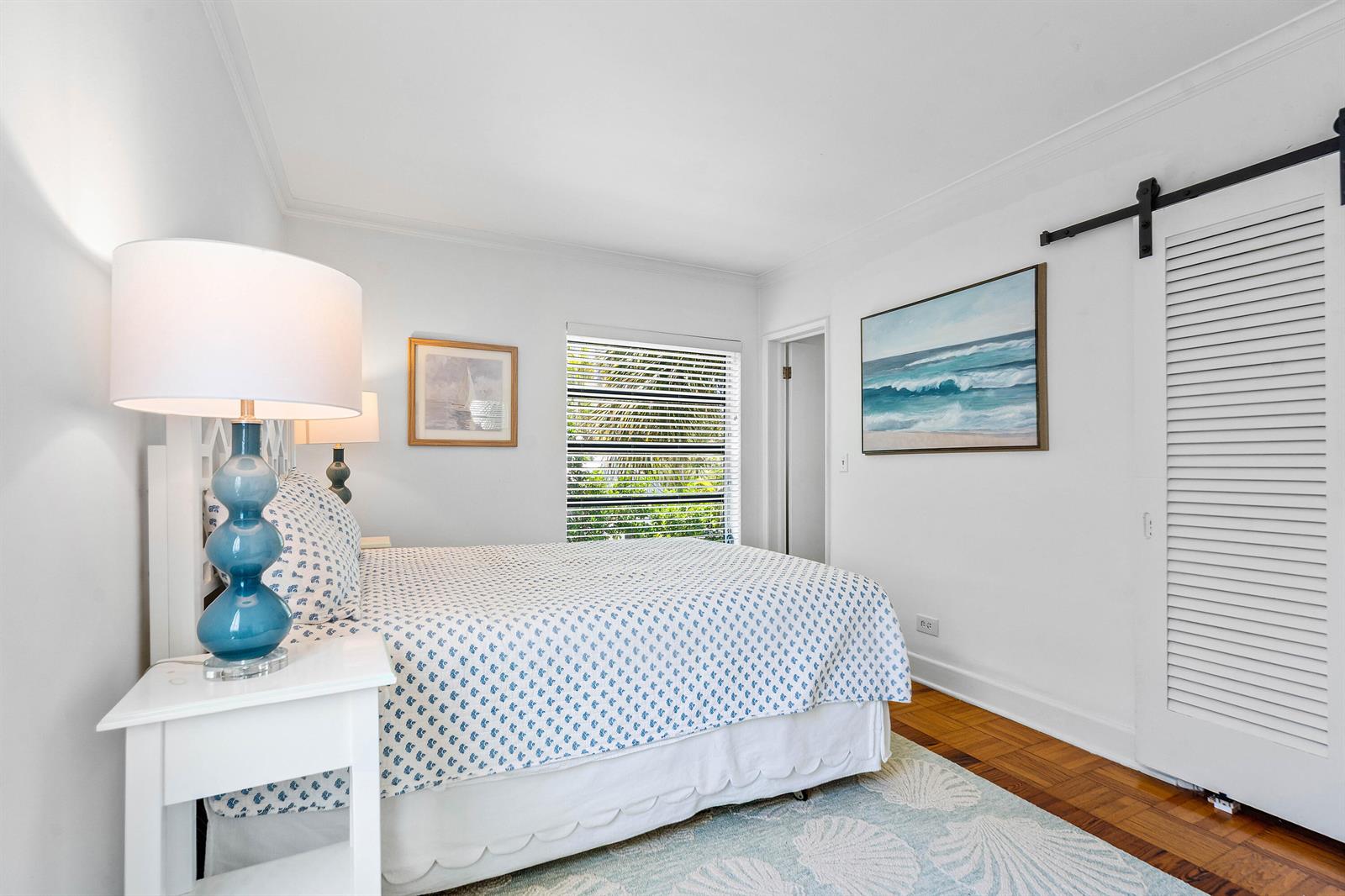 A bedroom features a bed with blue patterned bedding, a blue lamp, and a sliding door — 424 Chilean Avenue # 4, Palm Beach FL 33480, PALM BEACH, FL