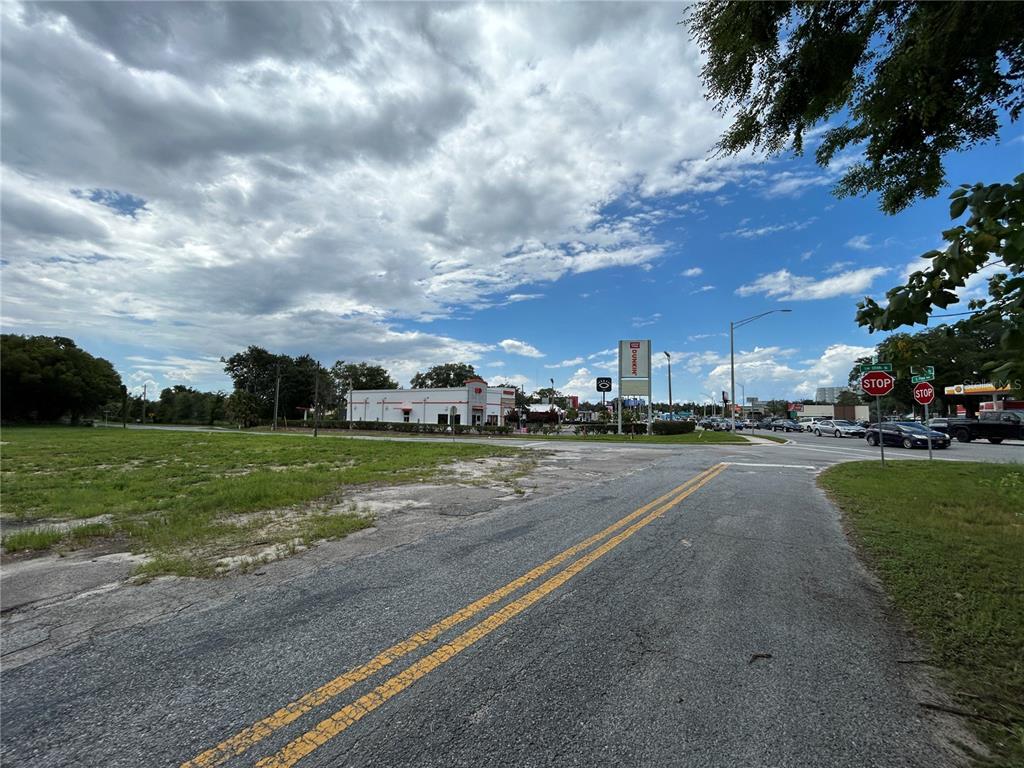 A view of a vacant grassy lot next to a road with a Dunkin' sign — 300 SW 18TH STREET, OCALA, FL