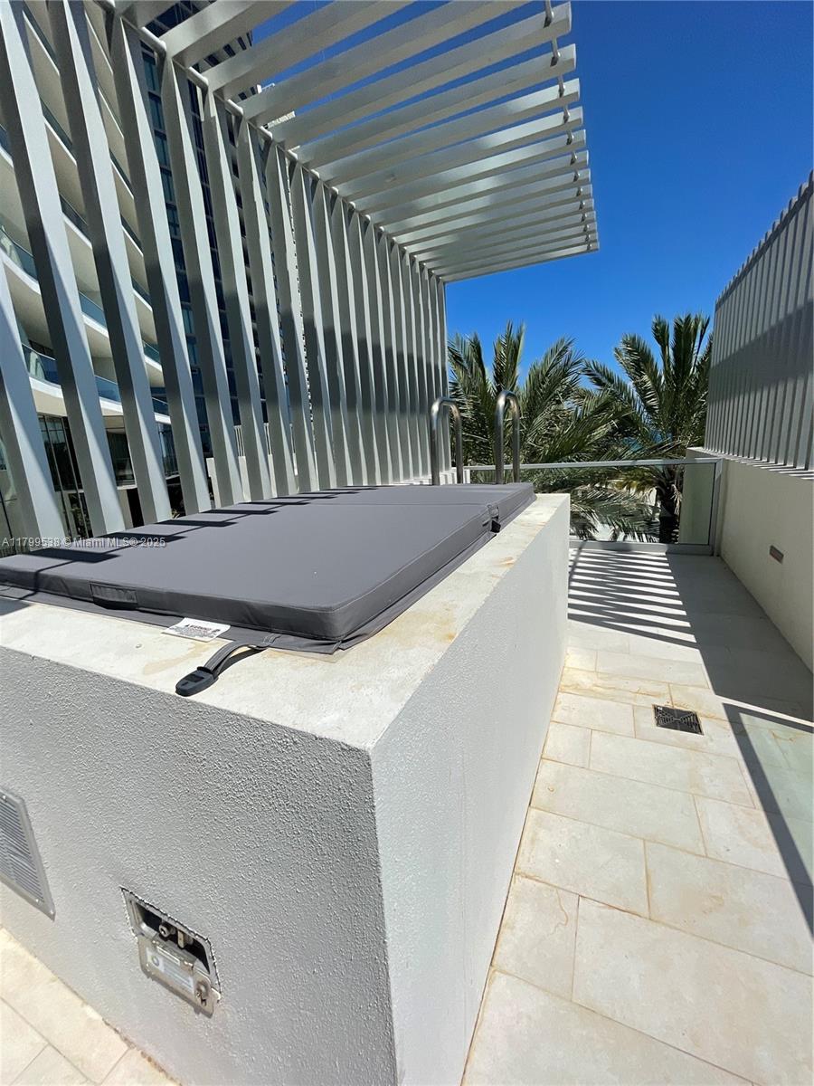 A covered hot tub sits on a tiled balcony with a modern slatted overhead structure — 18501 Collins Avenue # 27, Sunny Isles Beach FL 33160, SUNNY ISLES BEACH, FL