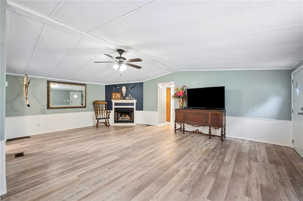 A living room features light wood-look flooring, a corner fireplace, and a ceiling fan — 13821 ROCKRIDGE ROAD, LAKELAND, FL