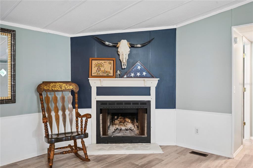 A room features a fireplace with a white mantel, a rocking chair, and blue walls — 13821 ROCKRIDGE ROAD, LAKELAND, FL