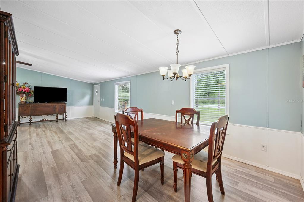 A dining area with wood-look flooring, a wooden table, and light blue walls — 13821 ROCKRIDGE ROAD, LAKELAND, FL