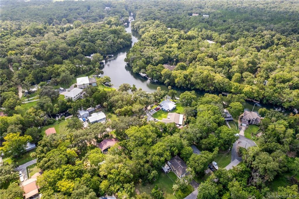 An aerial view shows houses nestled among dense trees along a winding river — 68 CANTERBURY ROAD, INGLIS, FL