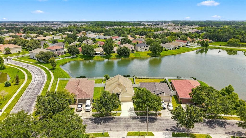 An aerial view shows a row of suburban houses situated along a lake — 31251 BACLAN DRIVE, WESLEY CHAPEL, FL