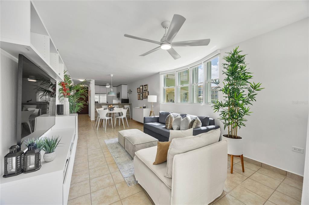 A dining area with a round white table, modern chairs, and a kitchen breakfast bar — Haudimar Beach Apartments 400 4466 ROAD UNIT H102, ISABELA, PR