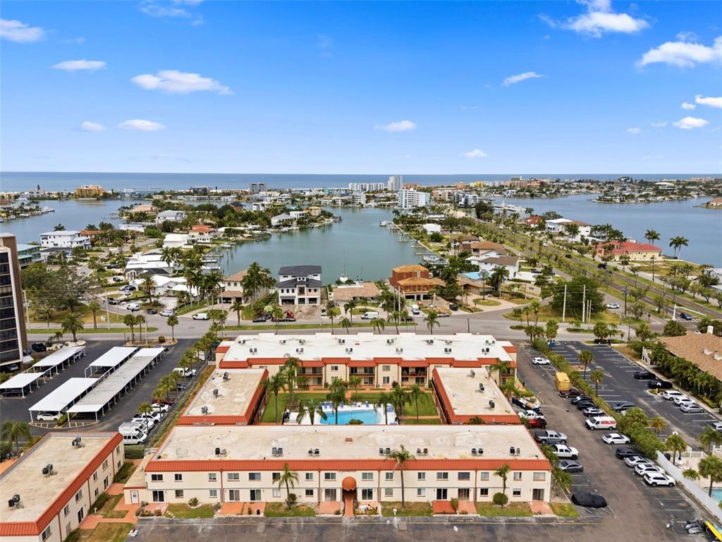 An aerial view shows a multi-story apartment complex with a central courtyard pool — 10365 PARADISE BOULEVARD UNIT 1, TREASURE ISLAND, FL