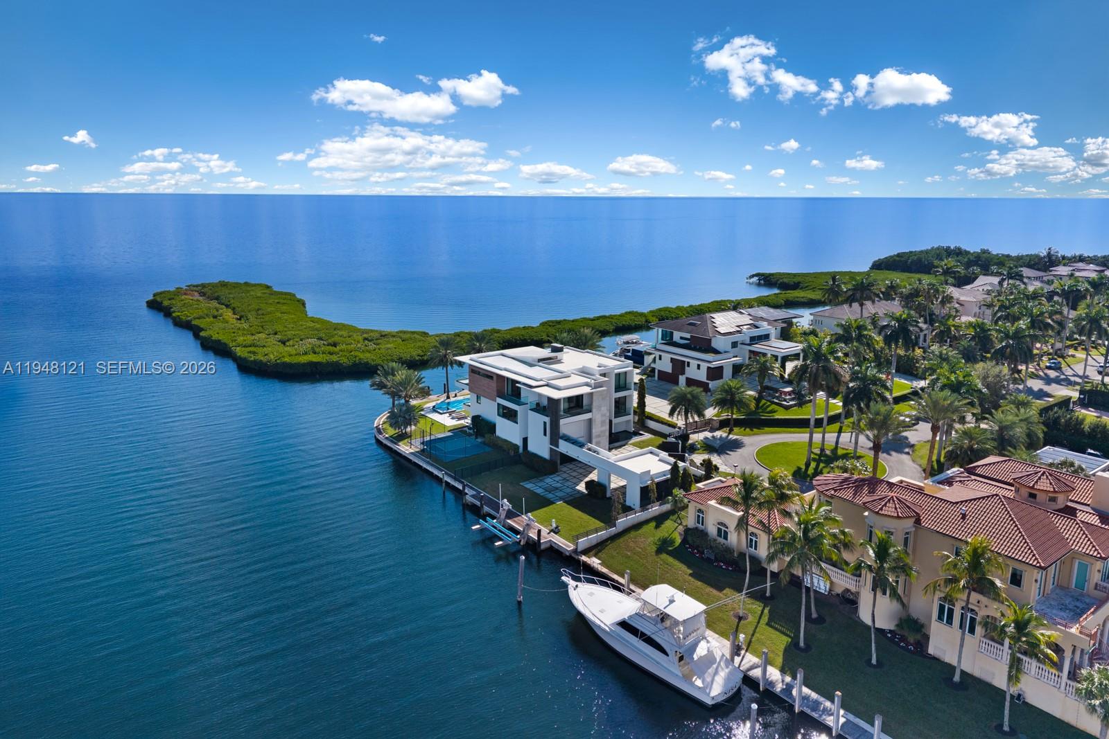 An aerial view shows luxury waterfront homes with private docks and boats on a bay — 13009 Mar St, Coral Gables FL 33156, CORAL GABLES, FL