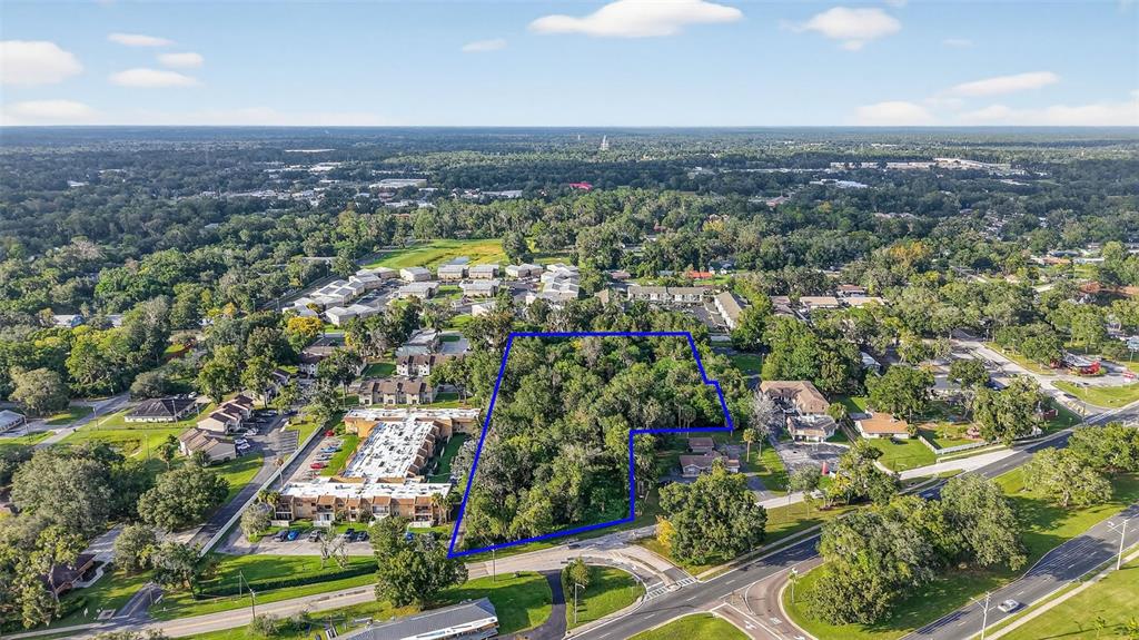 This aerial view shows a wooded plot of land outlined in blue near residential buildings — 2917 NE 3RD STREET, OCALA, FL