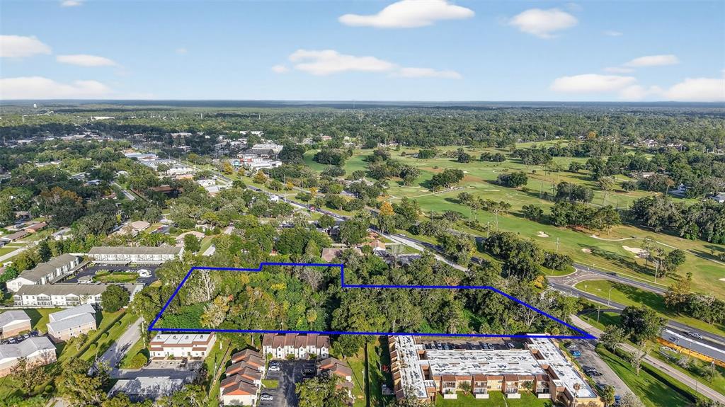 An aerial view shows a wooded lot outlined in blue, surrounded by residential apartment buildings — 2917 NE 3RD STREET, OCALA, FL