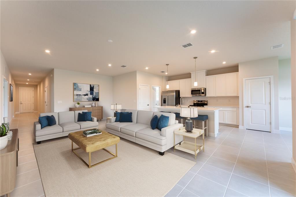 An open-concept living room and kitchen featuring light tile floors and white cabinetry — 123 VENETIAN PALMS BOULEVARD, NEW SMYRNA BEACH, FL