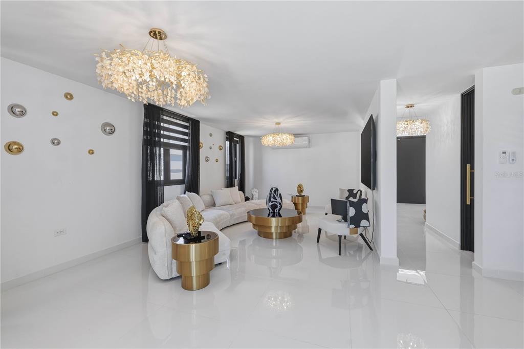 A modern living room features a curved white sofa, gold accents, and white tile flooring — 629 MAR DE BERING, DORADO, PR