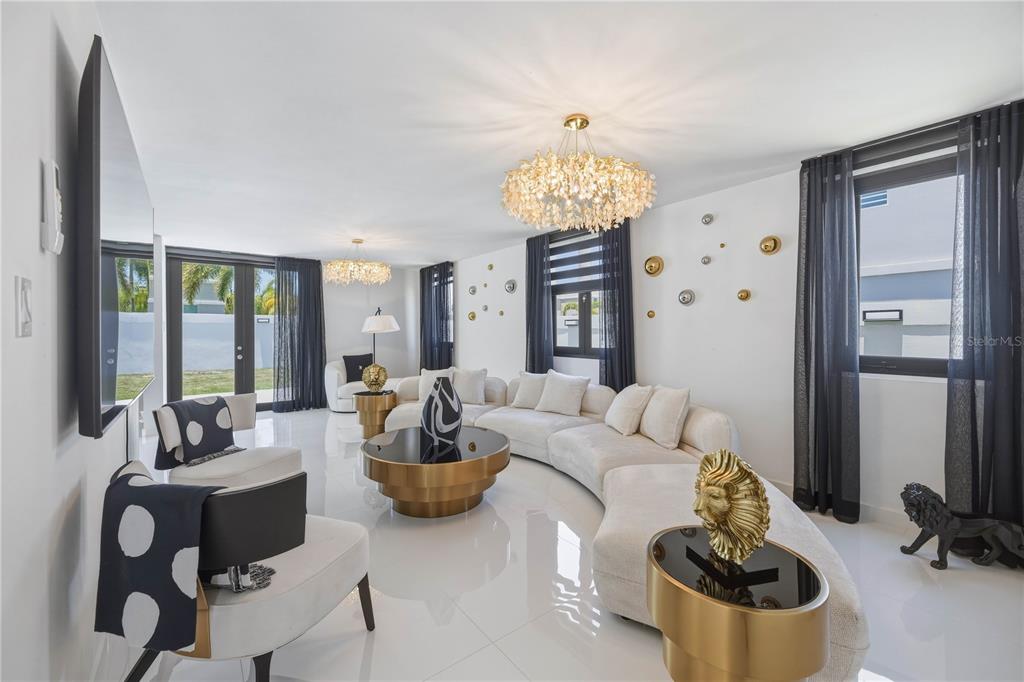 A modern living room features a curved white sofa, gold coffee table, and gold chandeliers — 629 MAR DE BERING, DORADO, PR