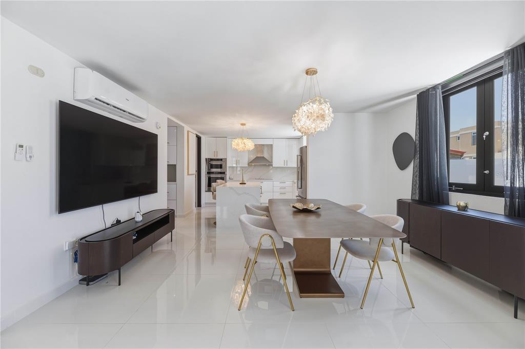A modern open-concept living and dining area features white tile floors and gold-accented furniture — 629 MAR DE BERING, DORADO, PR