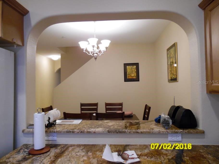 A dining area viewed through an arched opening from a kitchen with granite countertops — 12959 TIGERS EYE DRIVE, VENICE, FL