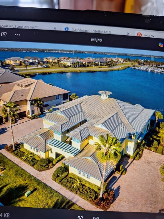 An aerial view of a large yellow house with a metal roof near a bay — 1121 RIVERSCAPE STREET, BRADENTON, FL