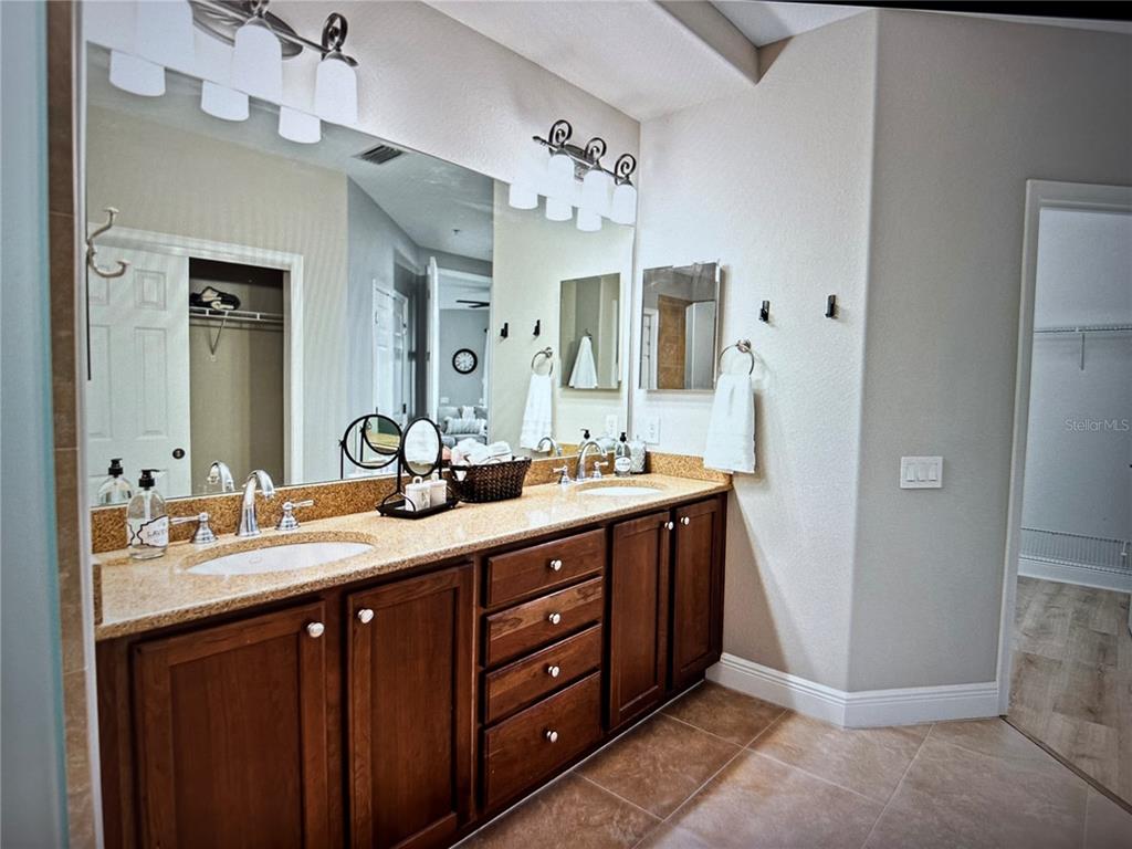 A bathroom features a double vanity with dark wood cabinets and a speckled granite countertop — 1121 RIVERSCAPE STREET, BRADENTON, FL