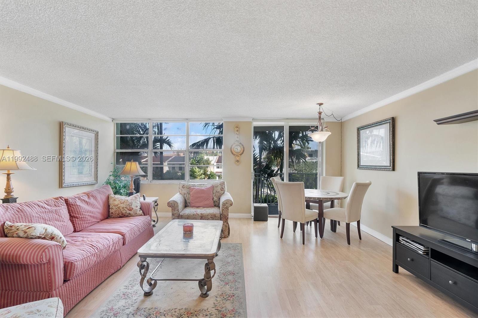 A living and dining area features light wood floors, a striped sofa, and large windows — 2100 Sans Souci Blvd # B111, North Miami FL 33181, NORTH MIAMI, FL