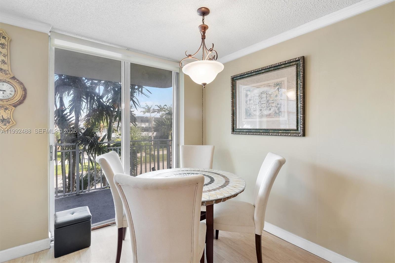 A dining area features a round mosaic table, four upholstered chairs, and a sliding glass door — 2100 Sans Souci Blvd # B111, North Miami FL 33181, NORTH MIAMI, FL