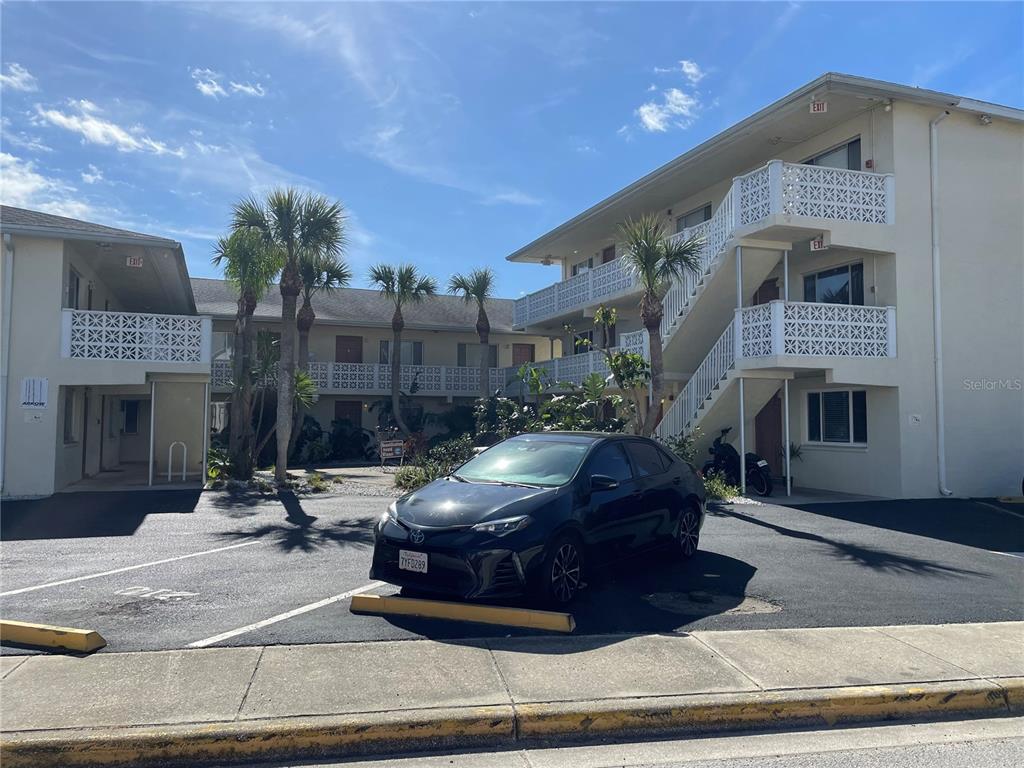 A black sedan is parked in front of a multi-story apartment building with exterior staircases — 102 S PENINSULA DRIVE UNIT 201, DAYTONA BEACH, FL