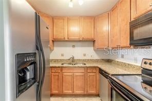 A kitchen with light wood cabinets, granite countertops, and stainless steel appliances — 102 S PENINSULA DRIVE UNIT 201, DAYTONA BEACH, FL