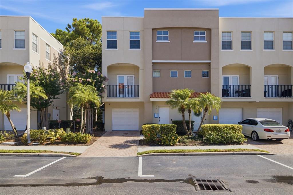 A multi-story townhouse exterior with a garage, balcony, and palm trees in front — 521 101ST AVENUE N, ST PETERSBURG, FL