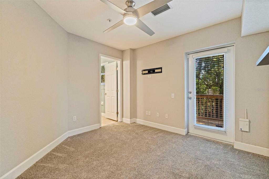 A carpeted room features a ceiling fan, a doorway to a bathroom, and a glass door — 521 101ST AVENUE N, ST PETERSBURG, FL