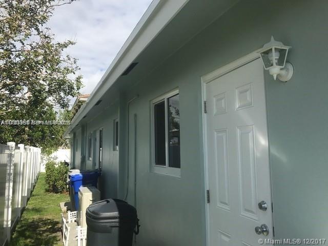 A side view of a light green house exterior featuring a white door and window — 1231 NE 23rd Ave, Pompano Beach FL 33062, POMPANO BEACH, FL