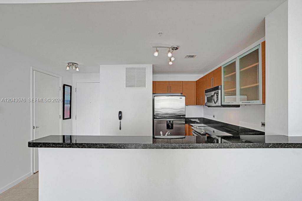 A kitchen features a black granite breakfast bar, stainless steel appliances, and wood-toned cabinetry — 725 NE 22nd St # 8B, Miami FL 33137, MIAMI, FL