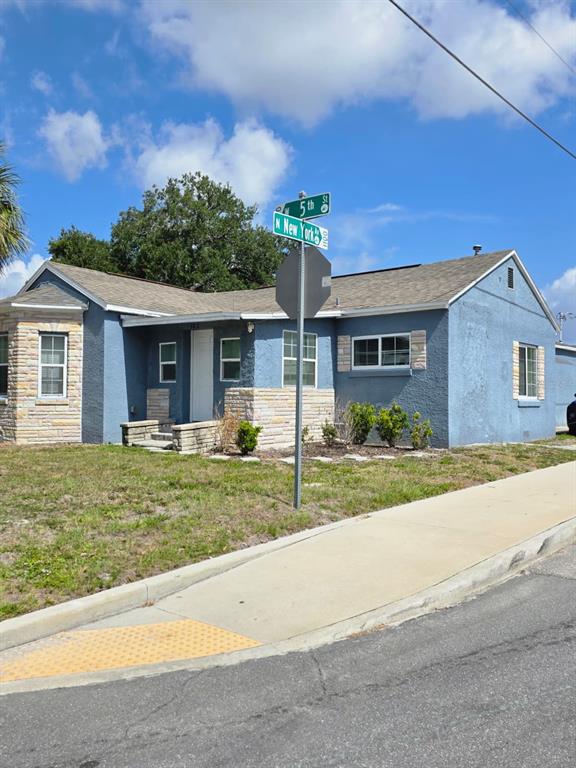 A blue, single-story house with stone accents sits at the corner of two streets — 303 W 5TH STREET, LAKELAND, FL