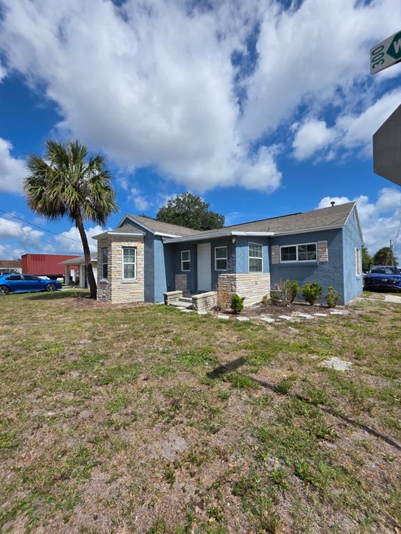 A blue, single-story house with stone accents and a palm tree in the front yard — 303 W 5TH STREET, LAKELAND, FL