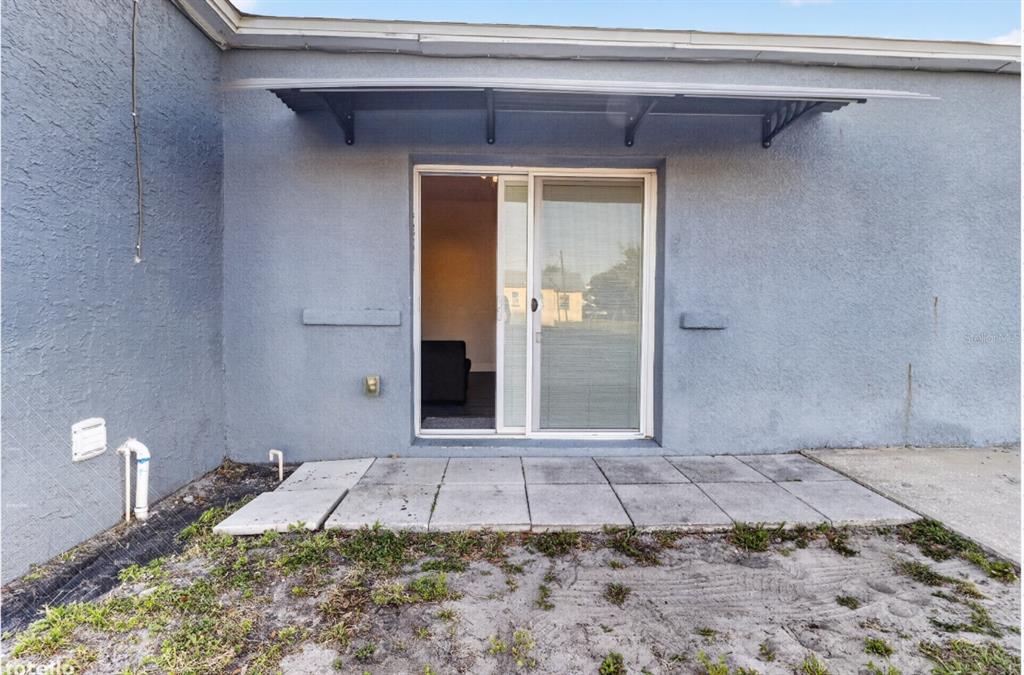 A sliding glass door leads to a small concrete patio outside a gray stucco wall — 303 W 5TH STREET, LAKELAND, FL
