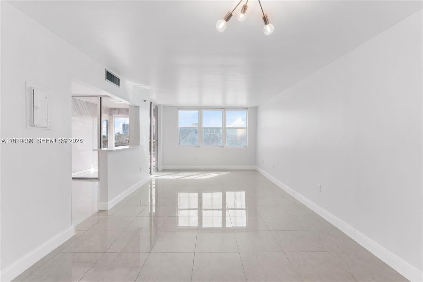A bright, empty living room features white walls, large windows, and polished light-colored floor tiles — 17890 W Dixie Hwy 501 Hwy # 501, North Miami Beach FL 33160, NORTH MIAMI BEACH, FL