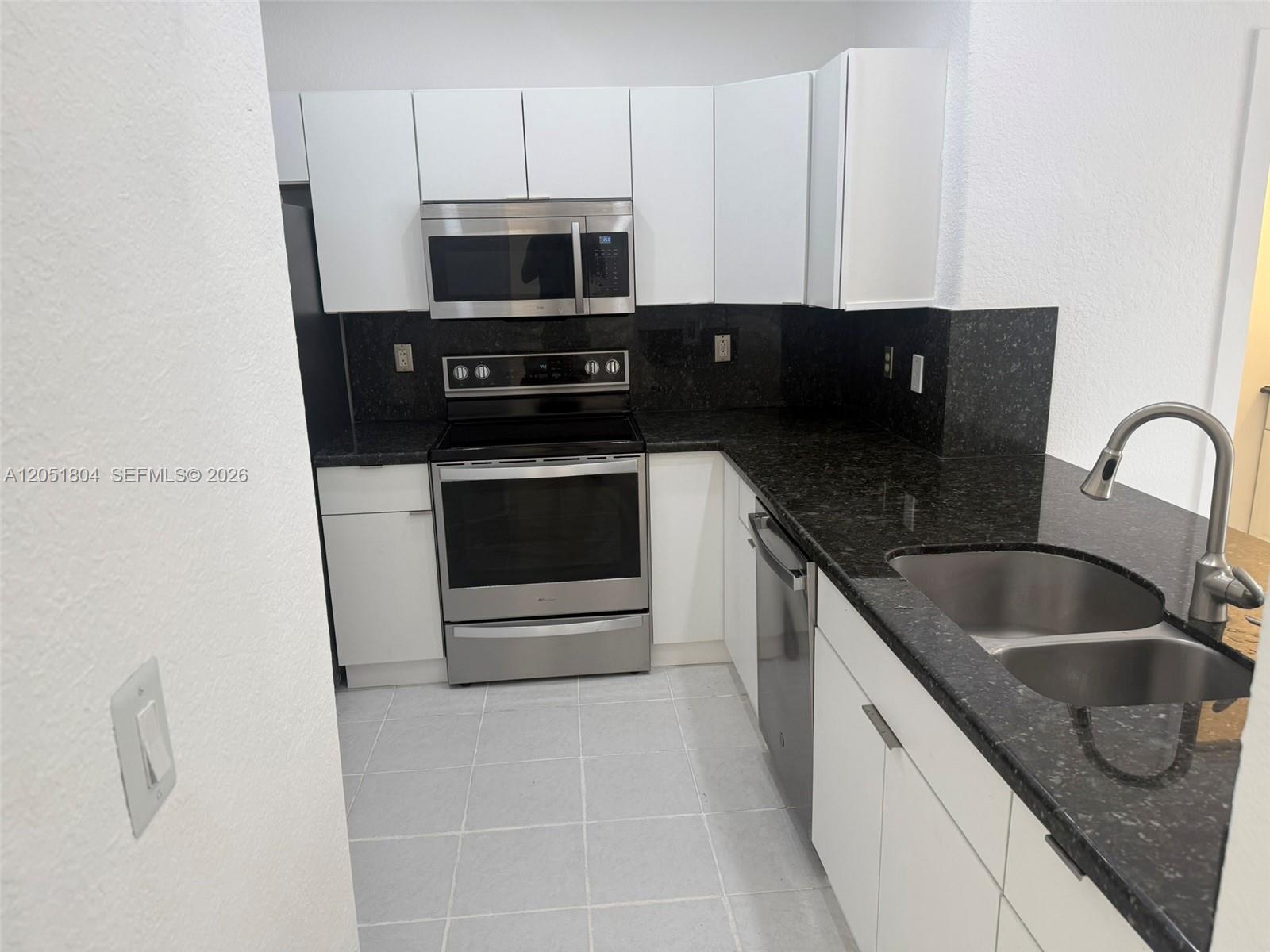 A kitchen features white cabinets, stainless steel appliances, and dark granite countertops — 3873 SW 171st Ter0, Miramar FL 33027, MIRAMAR, FL