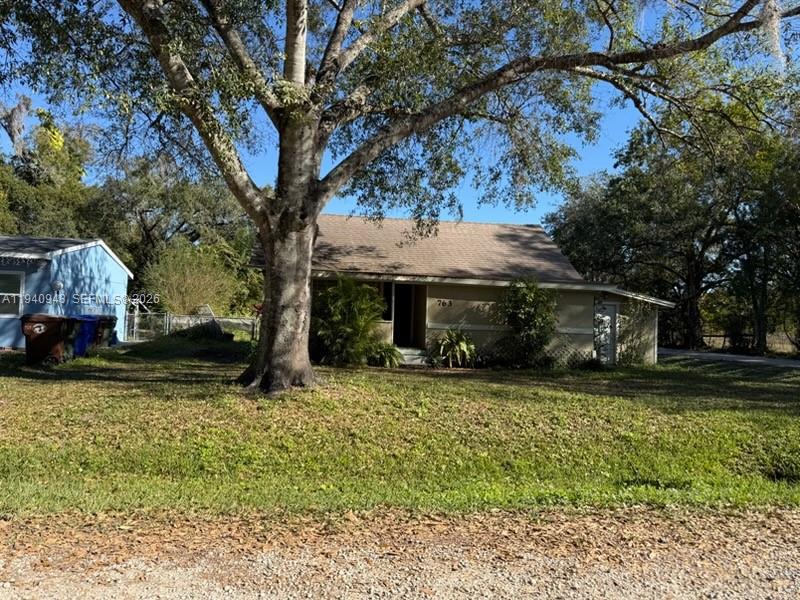 A single-story house with a brown roof sits behind a large tree on a lawn — 763 ROLFE STREET, Kissimmee FL 34741, KISSIMMEE, FL