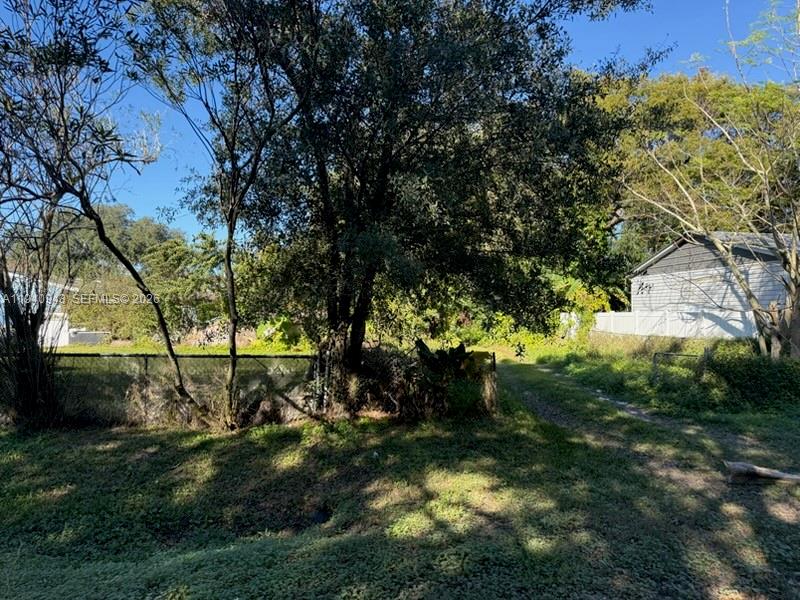 A grassy lot features a large tree, a chain-link fence, and a nearby house — 763 ROLFE STREET, Kissimmee FL 34741, KISSIMMEE, FL