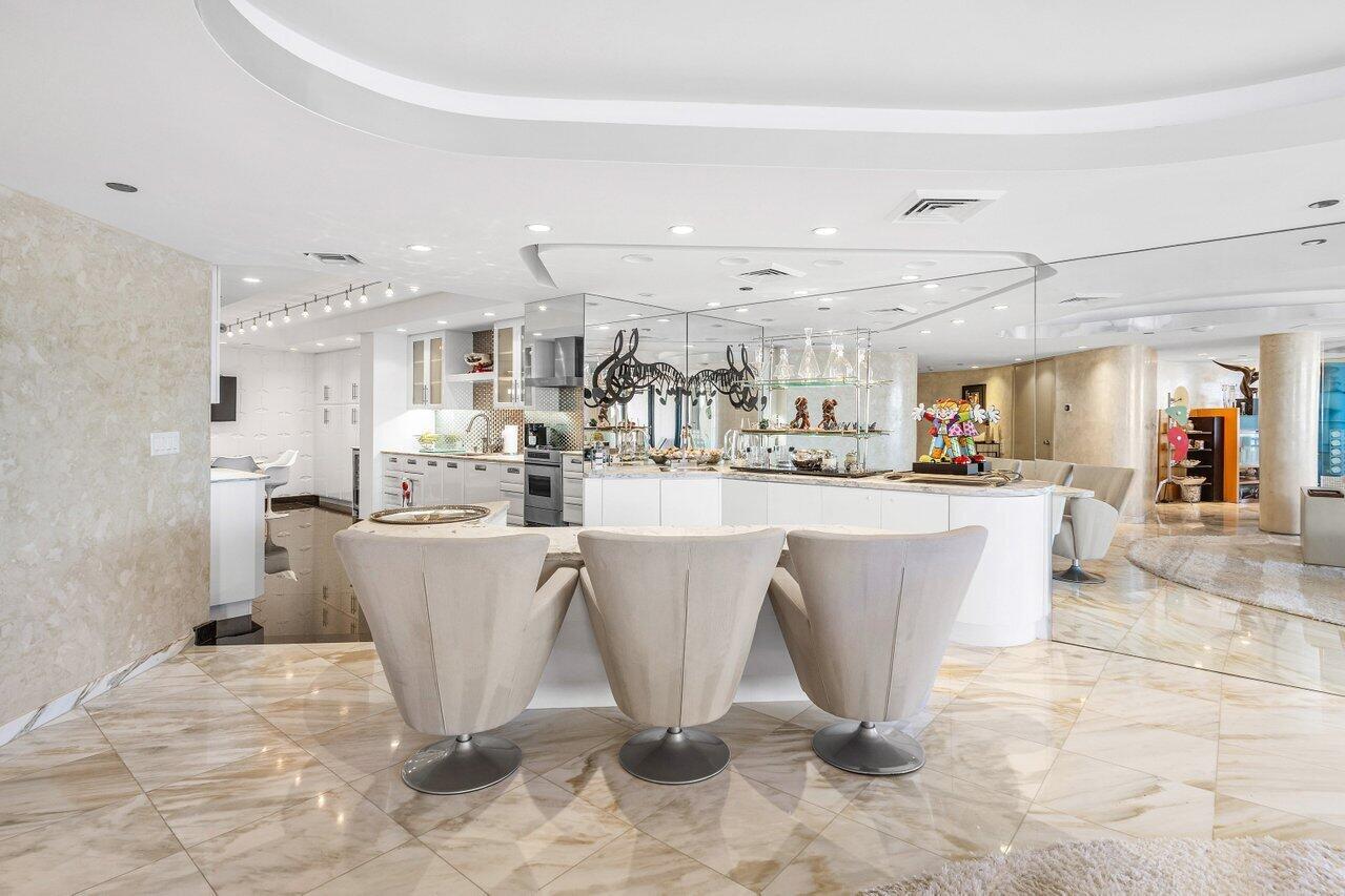 A modern kitchen features a curved breakfast bar with three chairs and marble flooring — 1500 S Ocean Boulevard, Boca Raton FL 33432, BOCA RATON, FL