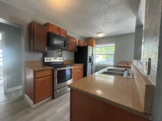 A kitchen features wood cabinets, stainless steel appliances, and a granite countertop with a sink — 1025 25TH STREET, ORLANDO, FL